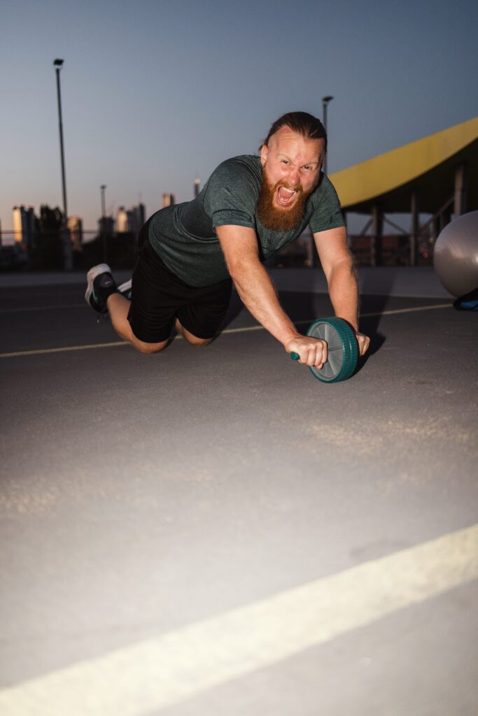 Personal Trainer Matthäus beim Bauchtraining mit dem Ab-Roller auf einem Parkdeck in Frankfurt am Main