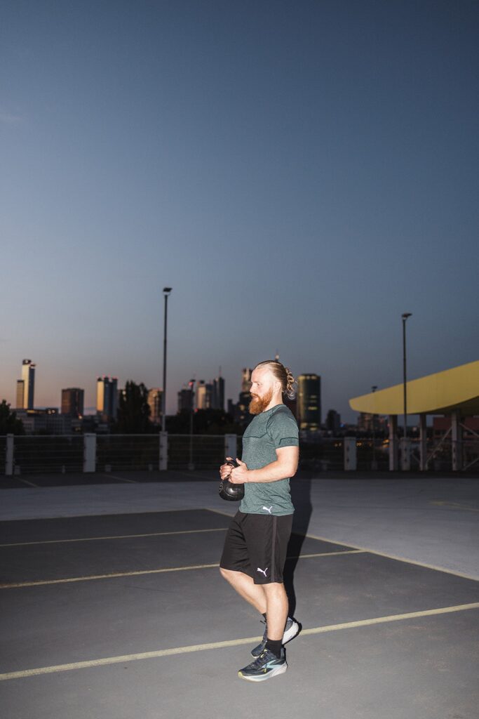 Kettlebell-Training in der Abenddämmerung vor der Skyline von Frankfurt