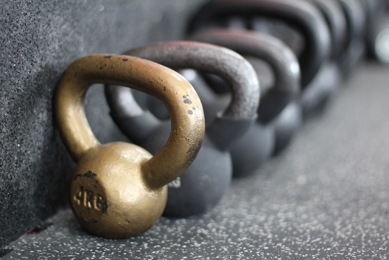 Mehrere Kettlebells in einer Reihe auf dunklem Boden